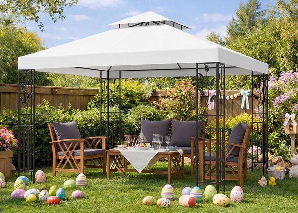 Set di mobili da giardino sotto un gazebo bianco, con sedie e tavolo in legno per una riunione di Pasqua, uova di Pasqua colorate sul prato verde, fiori in fiore e decorazioni primaverili in giardino soleggiato.