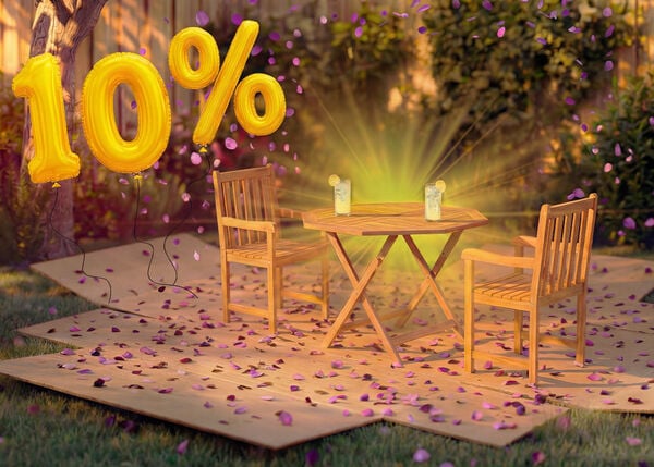 Tavolo da pranzo da esterno in legno con due sedie abbinate in un&rsquo;ambientazione da giardino, decorato con coriandoli rosa e palloncini dorati con &laquo;10% di sconto&raquo;, che mette in evidenza una promozione stagionale sui mobili da pranzo per esterni.