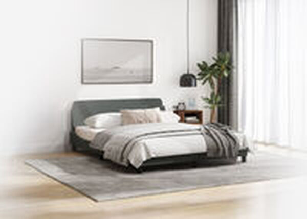Interno di una camera da letto minimalista con letto a piattaforma grigio scuro e biancheria grigio chiaro, una grande stampa paesaggistica incorniciata sopra la testiera, un comodino in legno e una pianta in vaso. Un tappeto grigio poggia su un pavimento in legno chiaro, con tende bianche leggere sullo sfondo.