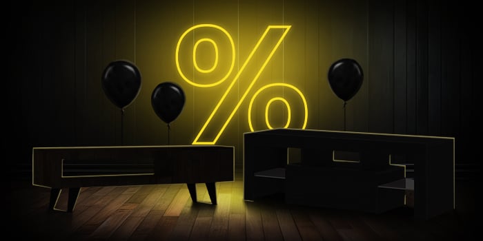  Mobile TV e palloncini neri davanti a un cartello giallo luminoso con il simbolo della percentuale su un pavimento di legno scuro.